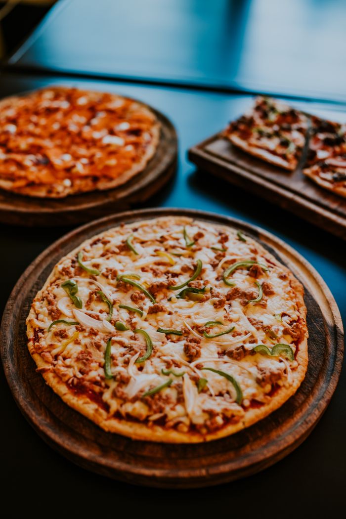 about-us-01 A mouthwatering display of freshly baked pizzas with various toppings on wooden trays.