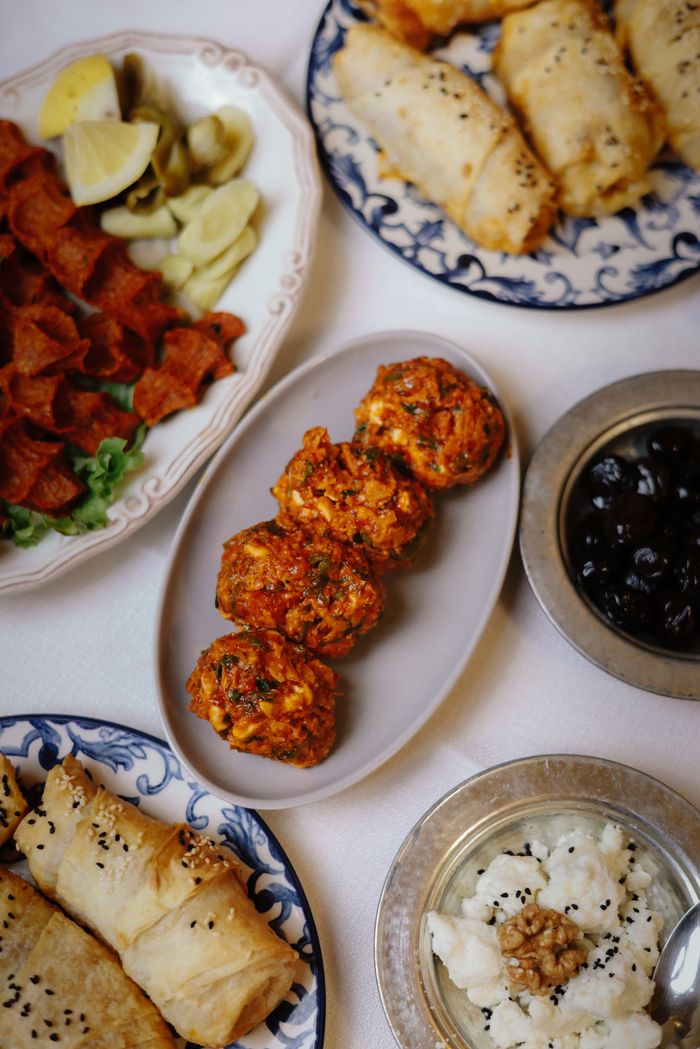 services-02 An assortment of traditional Turkish dishes served for Ramadan dinner featuring olives, pastry rolls, and red pepper balls.