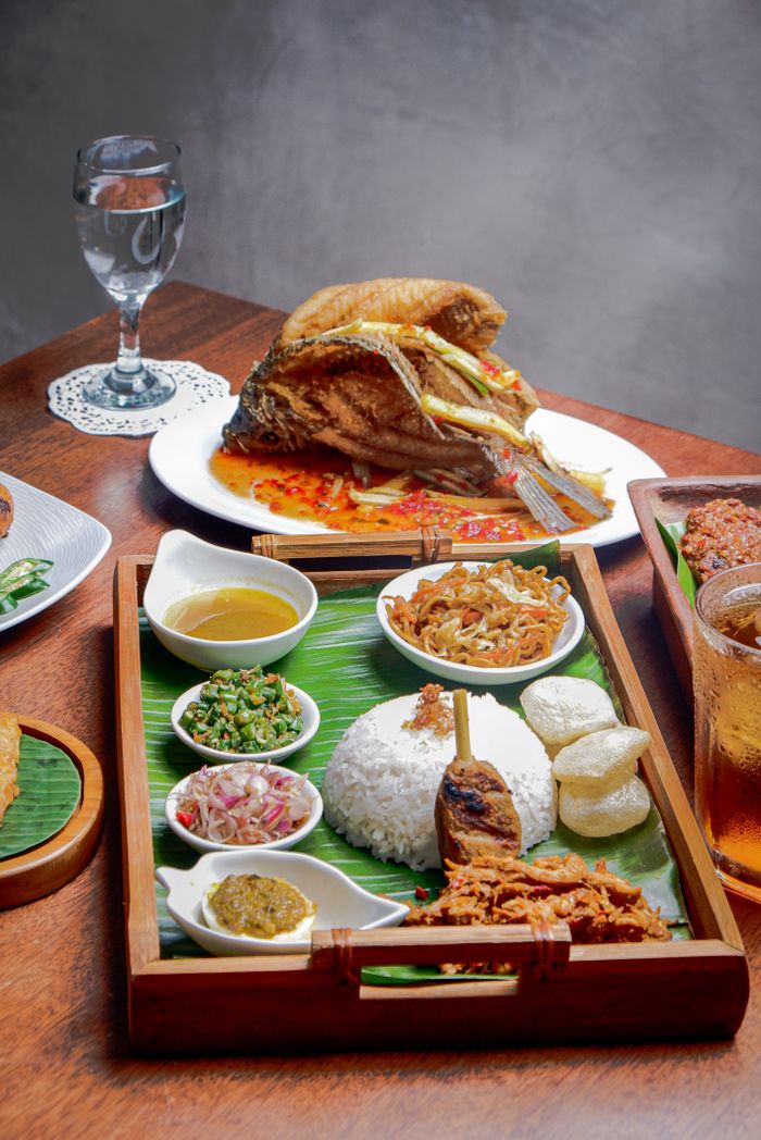 services-03 A colorful spread of traditional Indonesian cuisine with fish, rice, and condiments served on banana leaves.