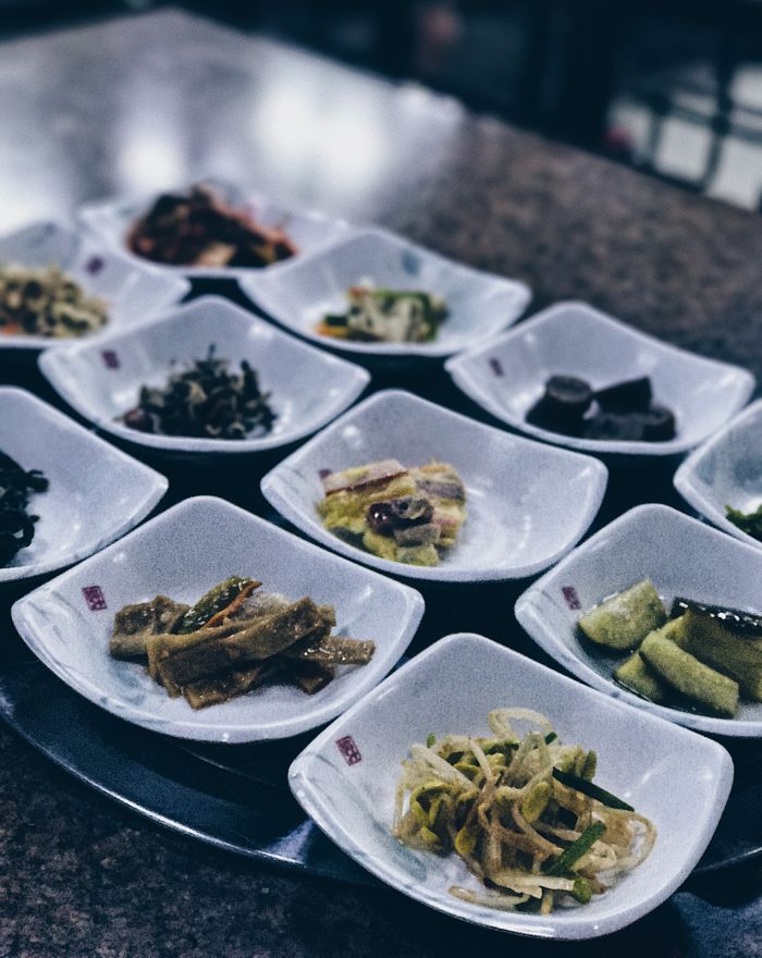 services-04 Close-up view of Korean side dishes, beautifully arranged on a table, highlighting traditional cuisine.